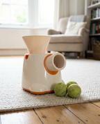 Automatic dog tennis ball launcher on a light wool rug with three tennis balls around it
