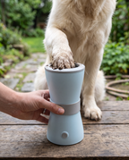 An automatic paw cleaning cup in use on a doorstep with a golden retriever's paw inside